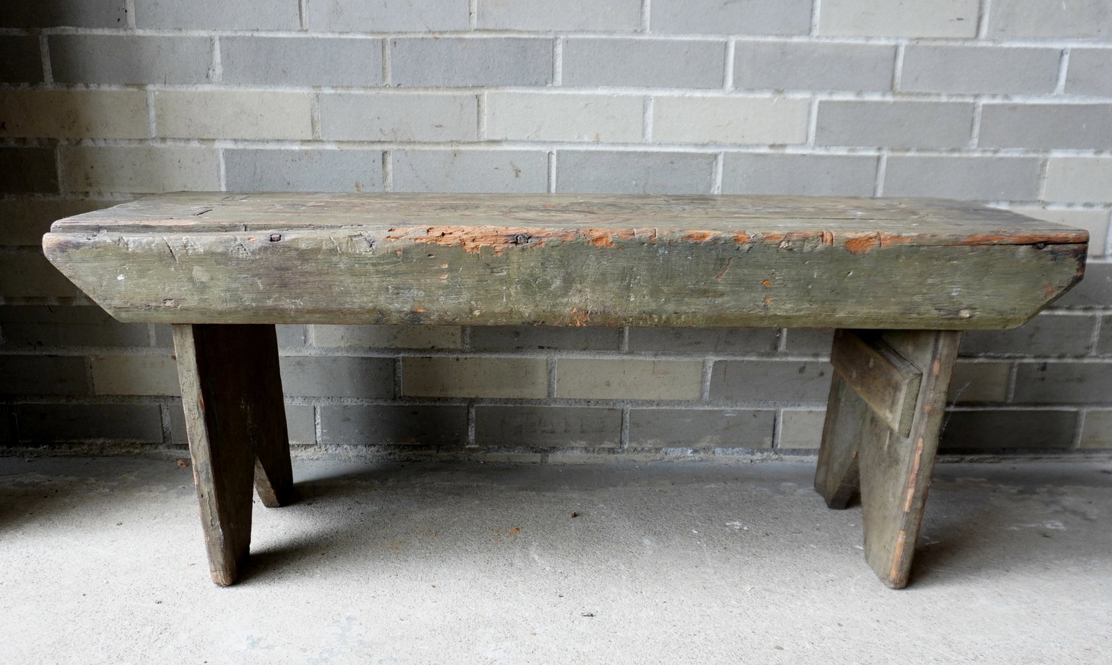 A primitive bench with see-through mortise construction and bootjack ends, circa 1800 - extensive: A primitive bench with see-through mortise construction and bootjack ends, circa 1800 - extensive use wear, small loss to top edge of one apron, considering its age, fair to good condition. Measures 3