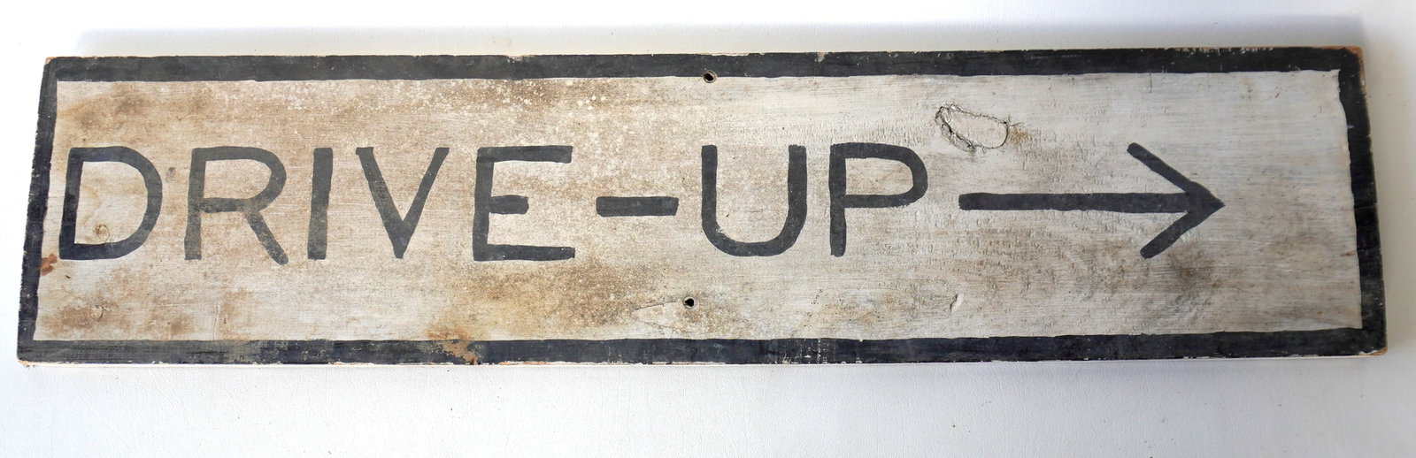 A wooden sign, with primitive hand painting marked "DRIVE-UP" with painted directional arrow, circa: A wooden sign, with primitive hand painting marked "DRIVE-UP" with painted directional arrow, circa 1950. Some use wear, needs cleaning, overall good condition. Measures 36 1/4" x 8 1/2". Provenance: 