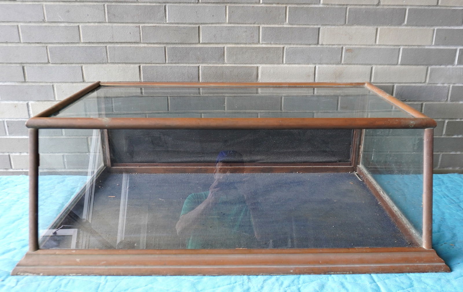 A slant front, country store table top showcase with metal frame and molded base, circa 1900.: A slant front, country store table top showcase with metal frame and molded base, circa 1900. Expected use wear and overall good condition. Measures 40"W x 27"D x 13 1/2"H. Provenance: From the Marni