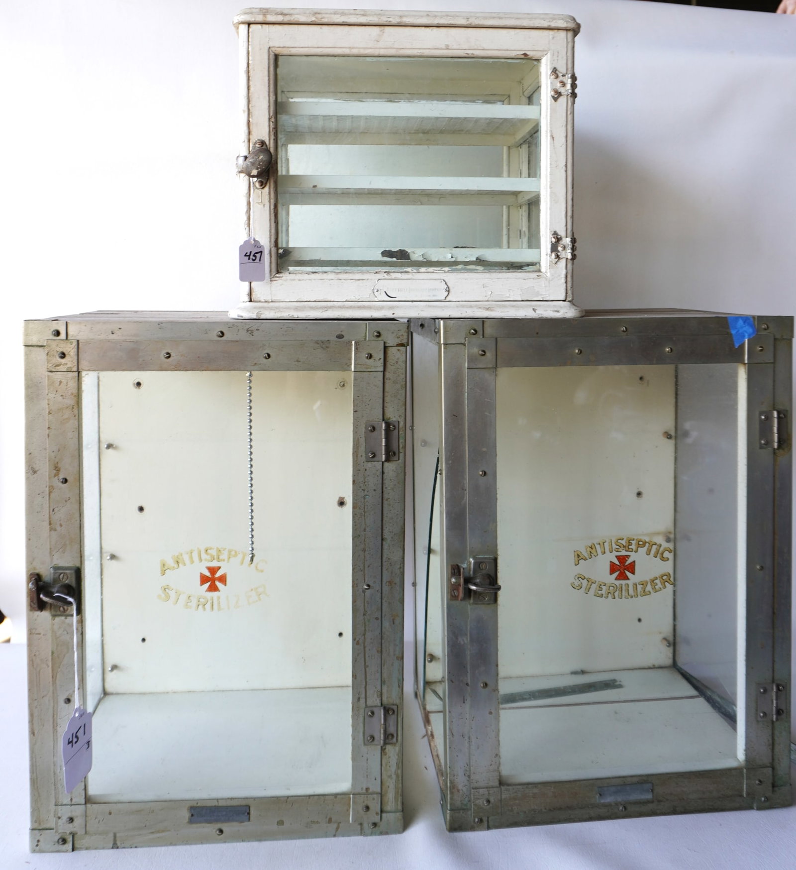 Three small table top medicine cabinets. The largest, 2 identical signed "Antiseptic Sterilizer" and: Three small table top medicine cabinets. The largest, 2 identical signed "Antiseptic Sterilizer" and measures 14 1/4"W x 11 1/2"D x 20"H - one is in good condition, the other with broken glass side pa