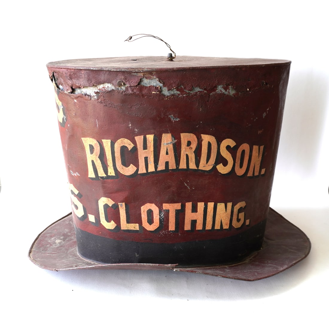 A large painted galvanized tin top hat trade store sign marked "HATS AND CAPS / RICHARDSON.: A large painted galvanized tin top hat trade store sign marked "HATS AND CAPS / RICHARDSON. CLOTHING" with shadow lettering. Condition: The paint is old but likely 2nd paint - there is a tear and dent