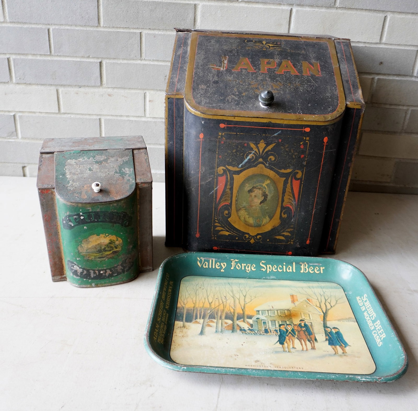 Three advertising articles including a tin "Japan" tea box - this is the largest in this lot: Three advertising articles including a tin "Japan" tea box - this is the largest in this lot measuring 13"W x 14"D x 13 3/4"H - wear to paint, bend in hinge, otherwise fair to good condition, a small 