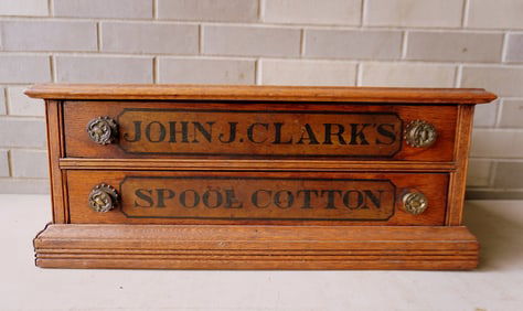 A John J. Clark's oak 2 drawer spool cabinet, very good condition. Measures 21 1/4"W x 15 1/2"D x 8