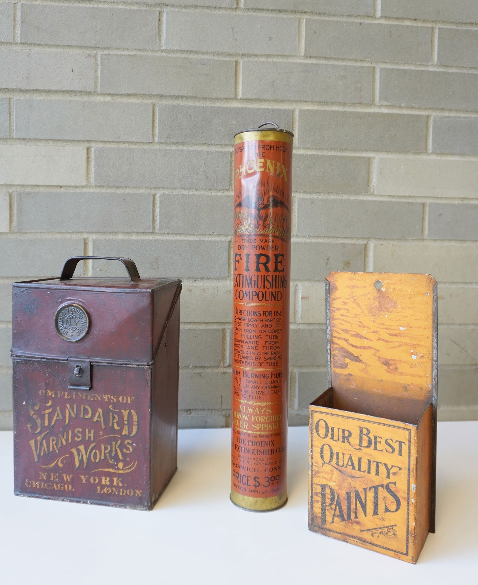 Three adverting tins including: "PHOENIX" dry powder fire extinguishing compound - 15 3/4'H - very: Three adverting tins including: "PHOENIX" dry powder fire extinguishing compound - 15 3/4'H - very good condition; a grain painted tin wall hanging box, probably for paint brushes, marked "Our Best Qu
