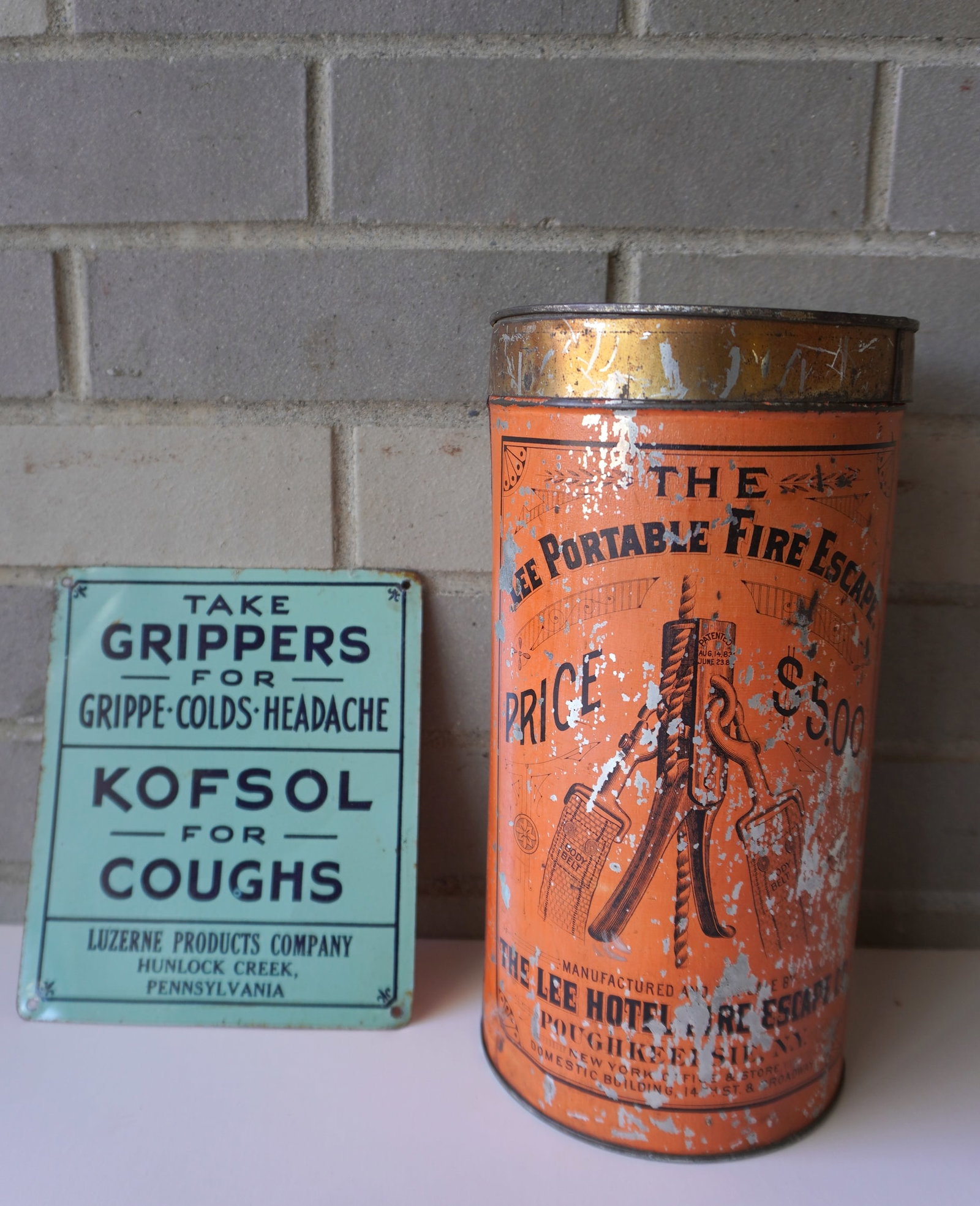 Two tin advertising articles: The first, a lithograph empty tin marked "The Lee Portable Fire Escape: Two tin advertising articles: The first, a lithograph empty tin marked "The Lee Portable Fire Escape / Price $5.00" from Poughkeepsie NY - some paint wear but overall good condition - 10 1/8"H x 5 1/4