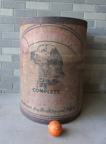 A large cylindrical dog grain bin having a lithograph of a dog on the front side signed "WORTHMORE /