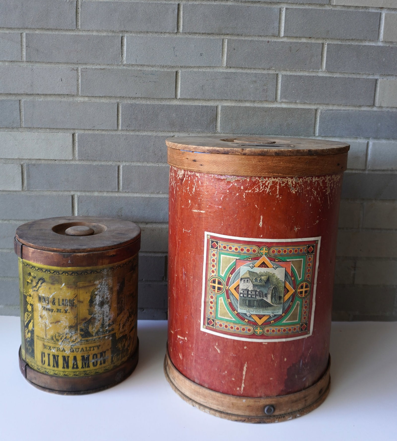 Two large cylindrical spice boxes with original lithograph labels and original wooden lids, late: Two large cylindrical spice boxes with original lithograph labels and original wooden lids, late 19th century - both with use wear. The largest measures 16 3/4"H x 12 1/4" diameter. Provenance: From t