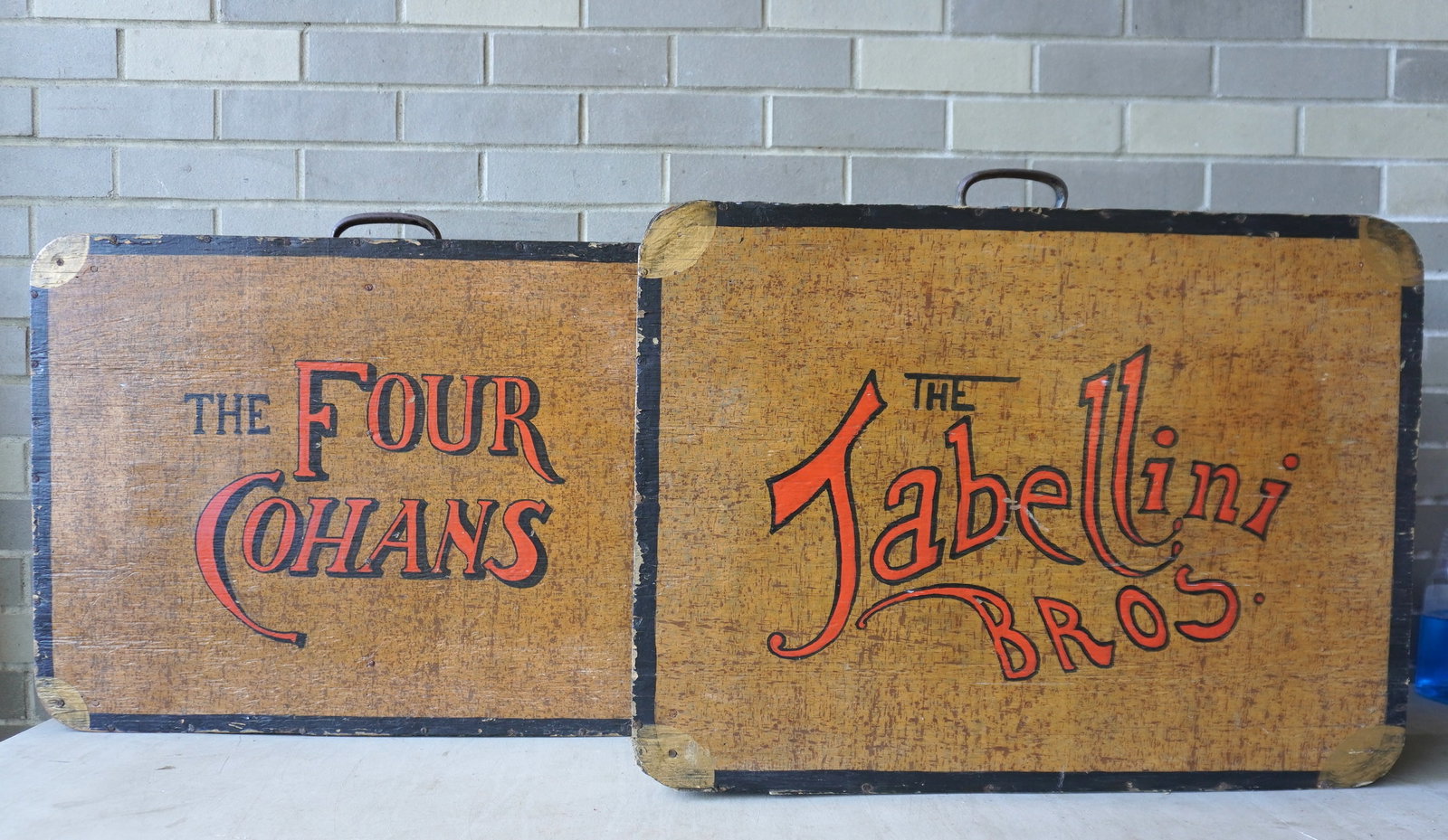Two suitcase shaped wooden stage props, including "The Four Cohens" and "The Tabellini Bros." - both: Two suitcase shaped wooden stage props, including "The Four Cohens" and "The Tabellini Bros." - both with use wear and in fair to good condition - each measures 27"W x 6"D x 21 3/4"H. Circa 1950. Prov