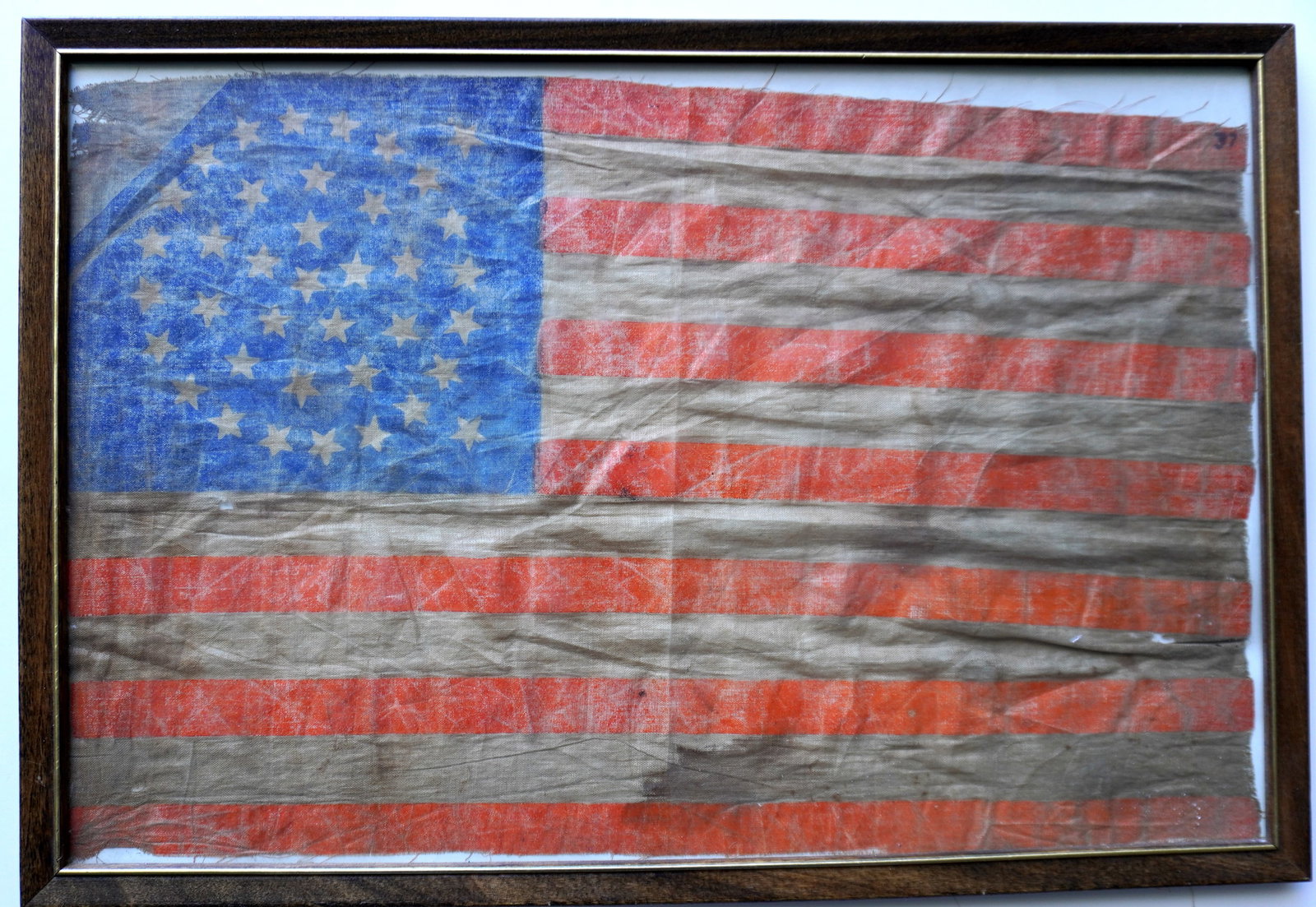 An American 38 star Centennial parade flag, offset medallion pattern (3 concentric rings of stars: An American 38 star Centennial parade flag, offset medallion pattern (3 concentric rings of stars surrounding center star - with 2 stars offset to the right). Some staining and wear around edges, over