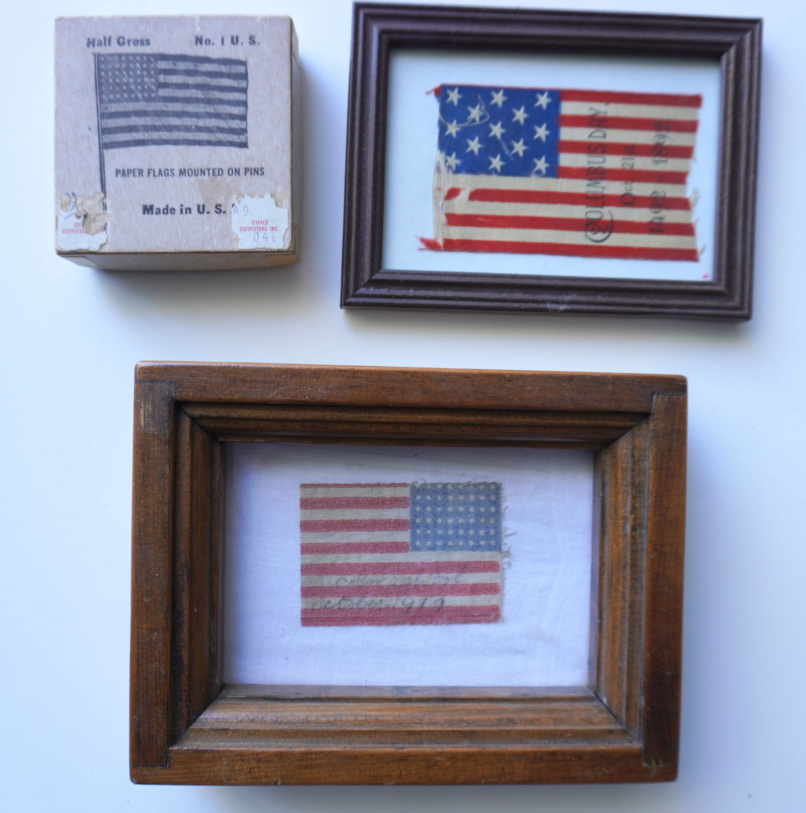 Two small American parade flags together with a box of 10 lithographed paper 48 star flags in: Two small American parade flags together with a box of 10 lithographed paper 48 star flags in original box marked "NO 1 U.S.". The first parade flag with 13 stars stamped "COLUMBUS DAY OCT 21st 1492-1