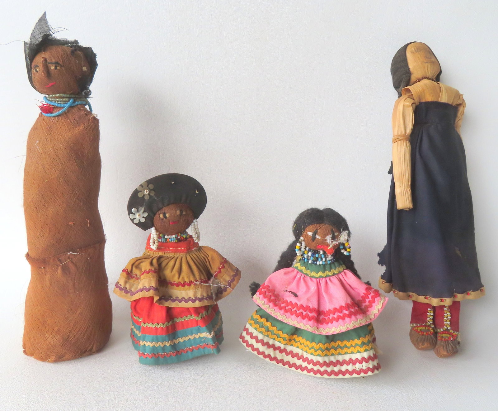 Four Seminole Indian Dolls, 3 palmetto dolls and 1 of corn husk doll. Two of the larger dolls with: Four Seminole Indian Dolls, 3 palmetto dolls and 1 of corn husk doll. Two of the larger dolls with losses to costumes, otherwise all in good condition. The largest, the corn husk doll, measures 11"L. 