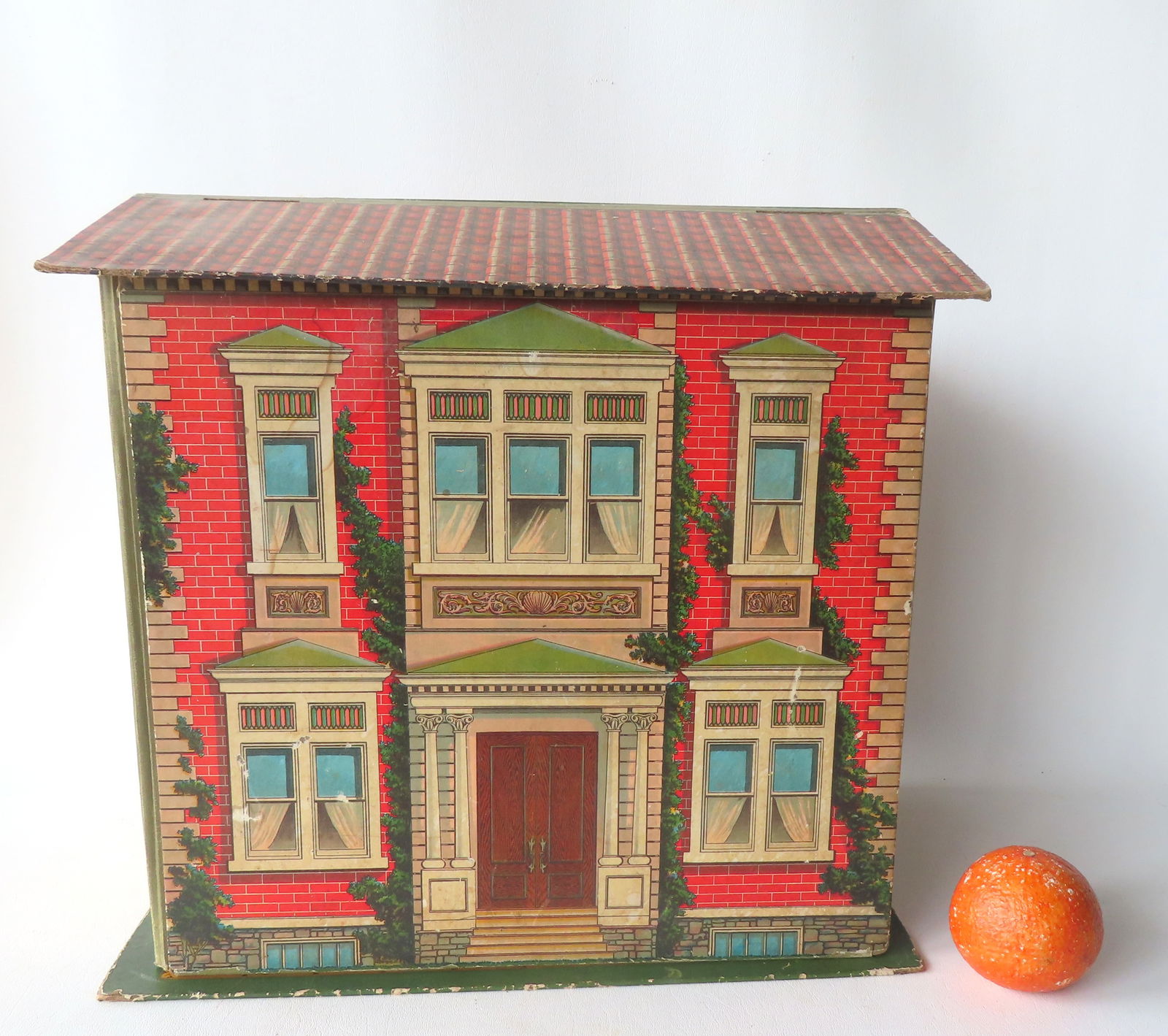 A lithographed cardboard Victorian doll house, probably McLaughlin, late 19th century - missing 2: A lithographed cardboard Victorian doll house, probably McLaughlin, late 19th century - missing 2 chimneys, else good condition. Measures 17"W x 11 3/4"D x 16"H. Provenance: From an early Connecticut