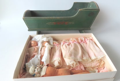 Grouping of small vintage dolls and a 19th century doll cradle. The doll cradle in original green