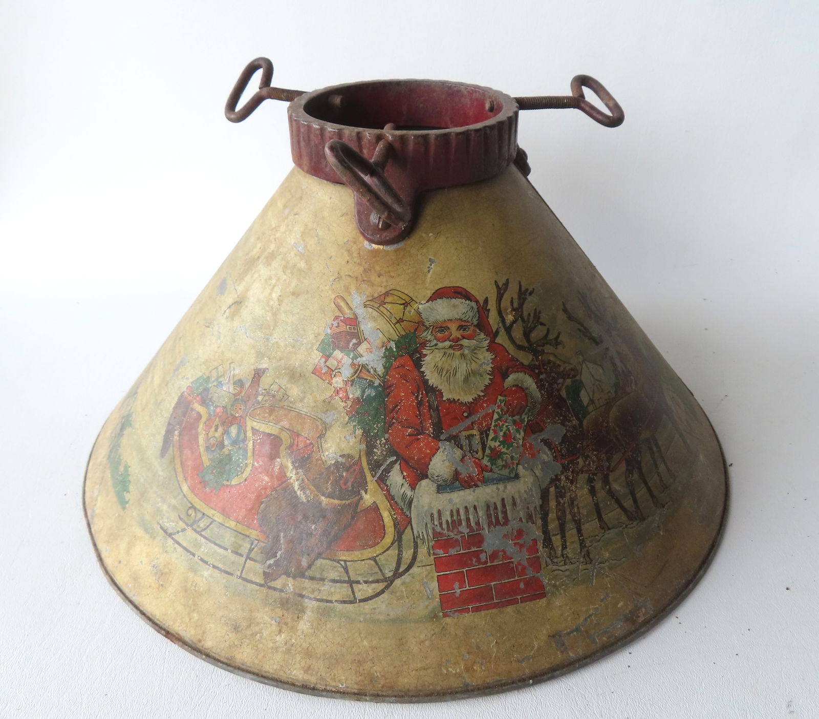 A lithographed tin and iron Christmas tree holder, decorated with Santa and reindeer on the front: A lithographed tin and iron Christmas tree holder, decorated with Santa and reindeer on the front panels. The base with original paper label marked "Noma Tree Stand" - some wear to the colored lithogr