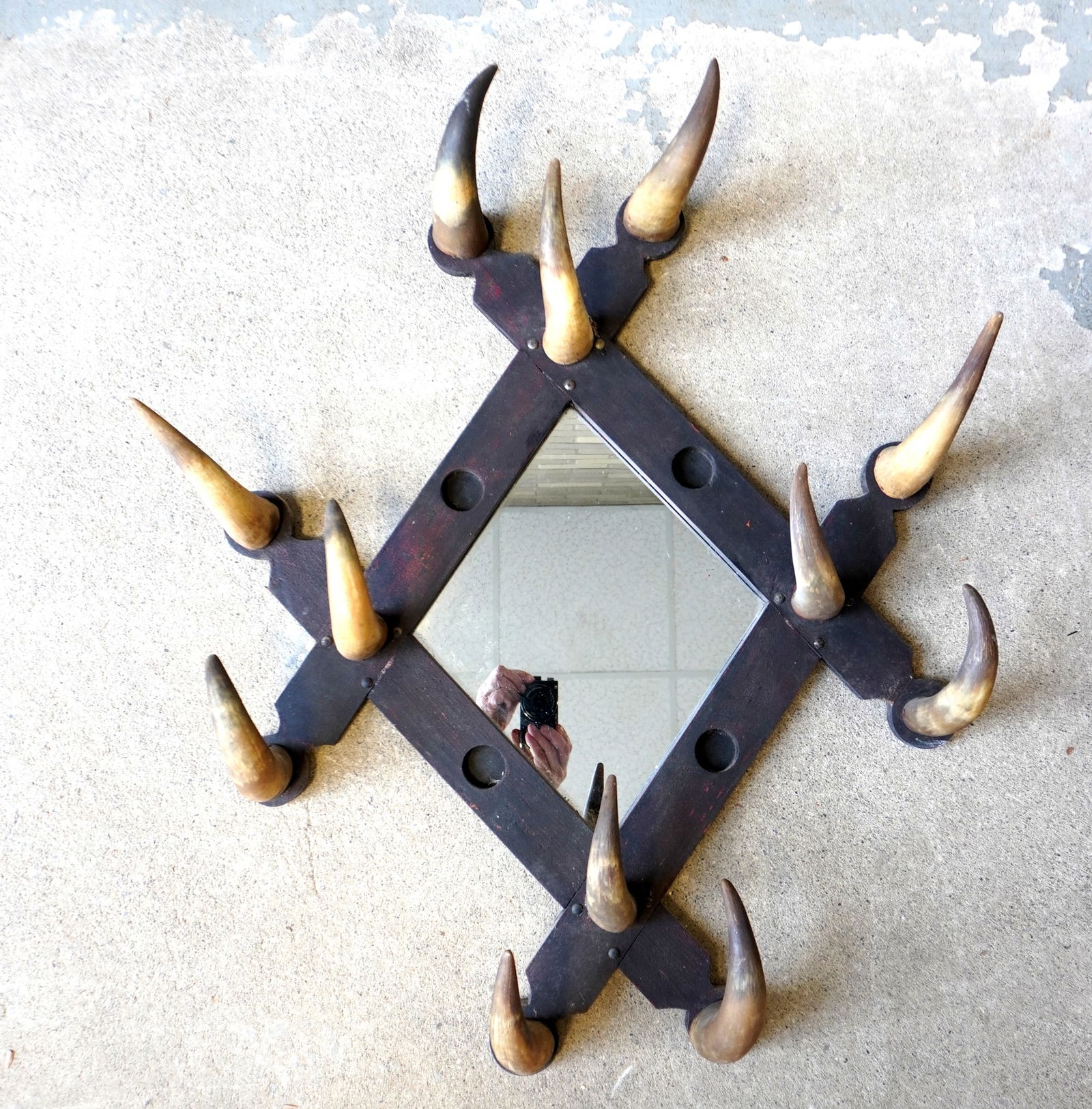 A rustic hat rack with mirror back, having applied cow horns around border, late 19th century, good