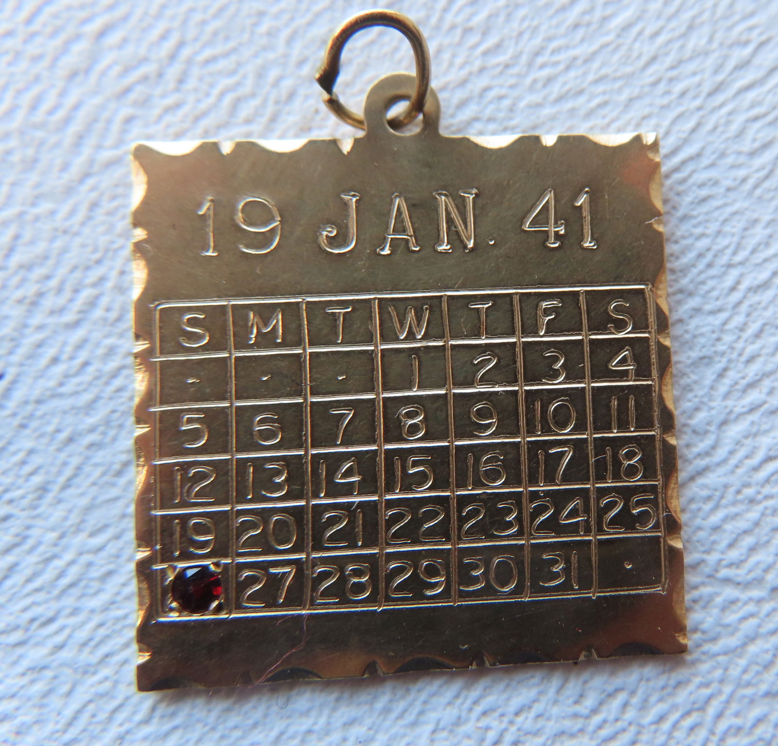 A marked 14k gold anniversary pendant/charm. One side with engraved calendar month of January marked (1 of 2)