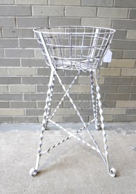 A Victorian wire sewing basket (or plant stand) on wrought iron stand with twisted legs leading to