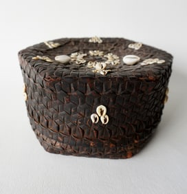 A hexagonal shaped plaited covered basket decorated with Cowrie shells, tightly woven with no