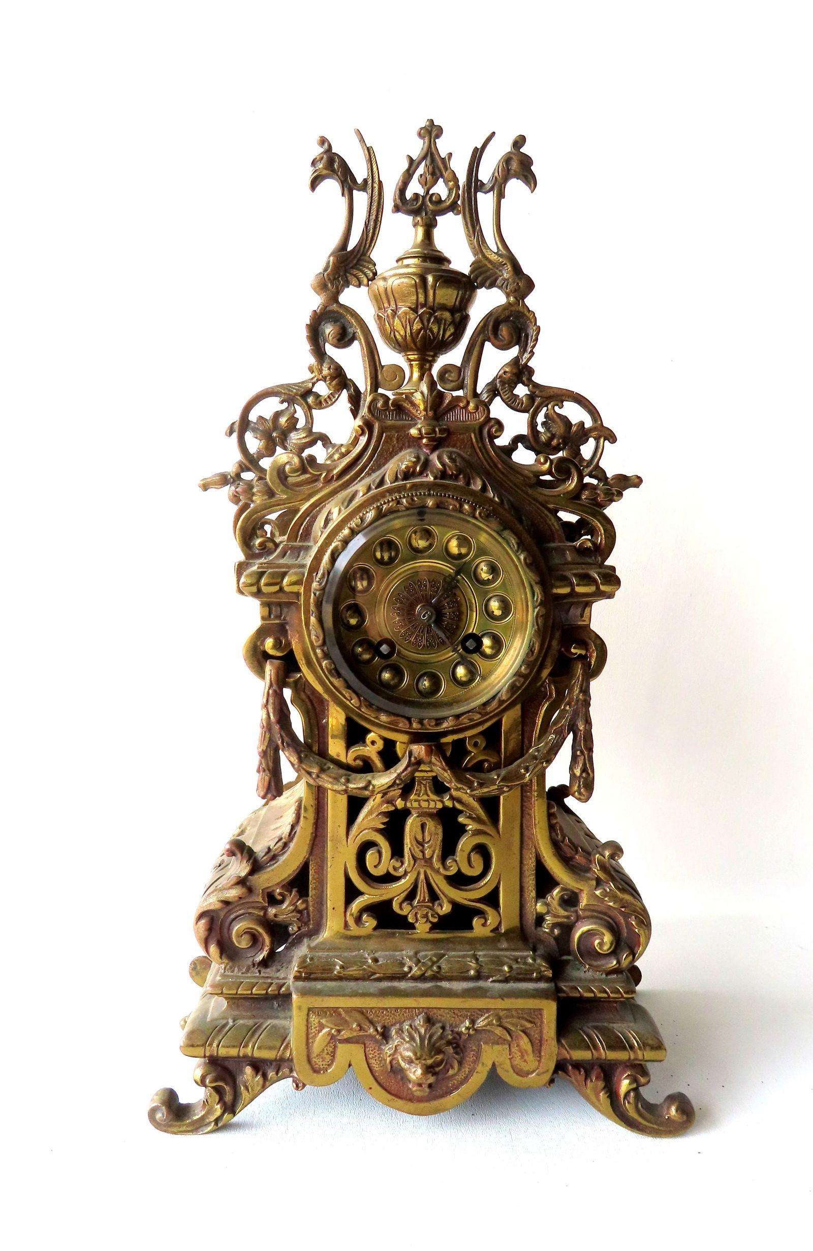An ornate French style brass mantle clock having an urn finial flanked by winged griffins, scrolls (1 of 9)