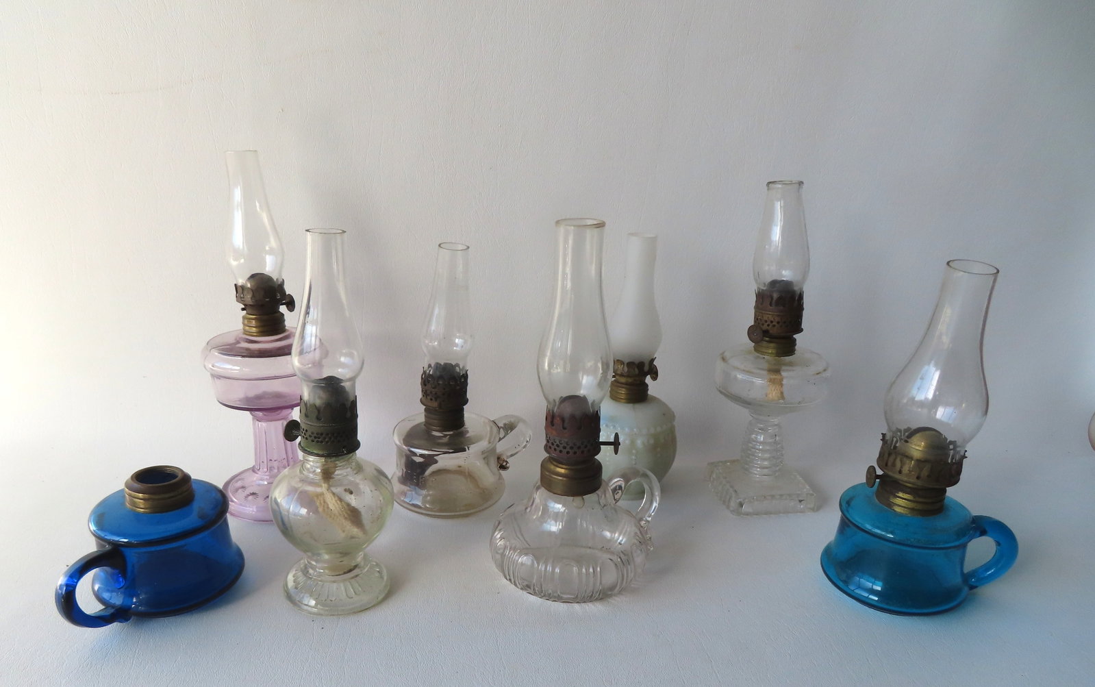 Grouping of 8 miniature oil lamps including 2 finger lamps in blue, 1 colorless marked "Little: Grouping of 8 miniature oil lamps including 2 finger lamps in blue, 1 colorless marked "Little Butter Cup", one in violet color, another marked "Handy's", etc. Most in very good condition, 19th centur