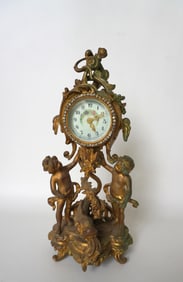 An ornate French style mantle clock decorated with cherubs, dolphin, grapes and vine and having a