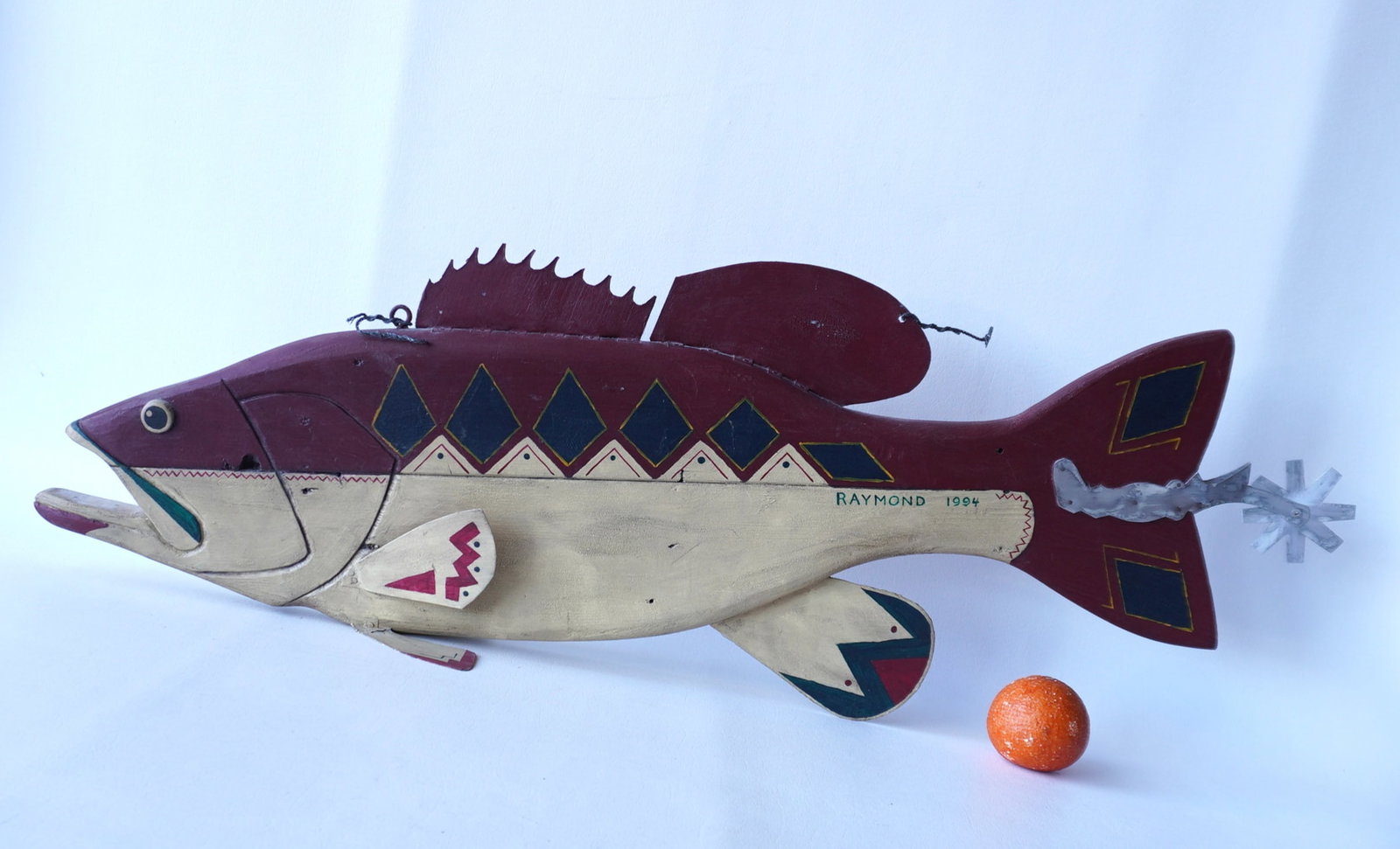 Jeff Raymond, folk art fish carving (1949-2022, Poughkeepsie and Red Hook NY). A carved wooden: Jeff Raymond, folk art fish carving (1949-2022, Poughkeepsie and Red Hook NY). A carved wooden stylized fish decorated in the Western style with Native American designs and cowboy spur attached to the