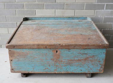 A primitive country store desk in original worn blue paint, early to mid 19th century. Slanted lid,