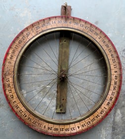 An old carnival gaming wheel in the form of a bicycle wheel, in original red and white paint with