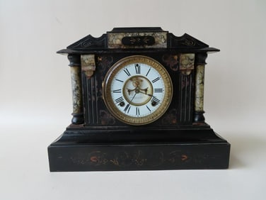 An Empire style slate mantle clock with incised decorations and marble embellishments including side