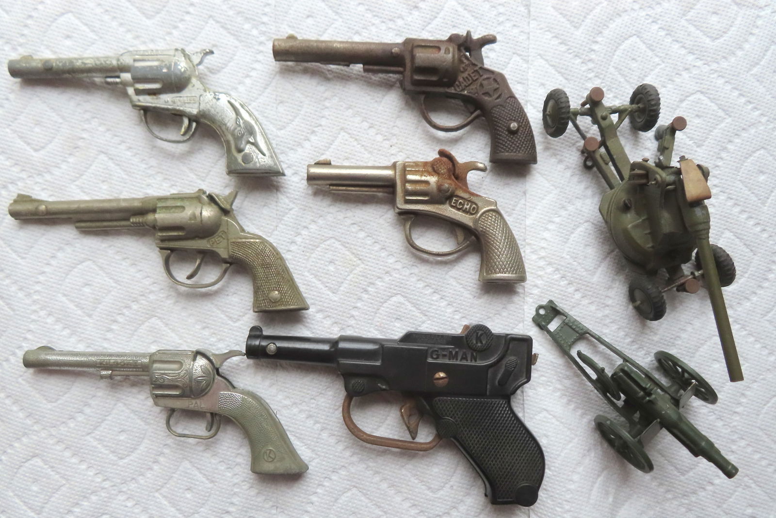 Grouping of 6 vintage cap guns and 2 vintage "Britains Ltd. London" diecast howitzers (missing: Grouping of 6 vintage cap guns and 2 vintage "Britains Ltd. London" diecast howitzers (missing projectiles) - the larger howitzer with break in on axel, else good condition - the other in very good co