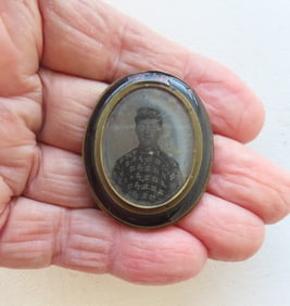 A miniature framed ambrotype photo of a young man wearing field cap and checkered buttoned up shirt