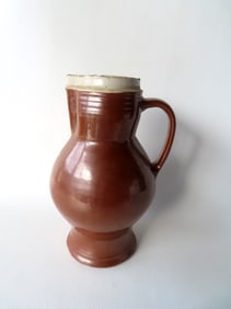 A bulbous stoneware jug, brown glaze, tooled handle, concentric rings under rim and around base,