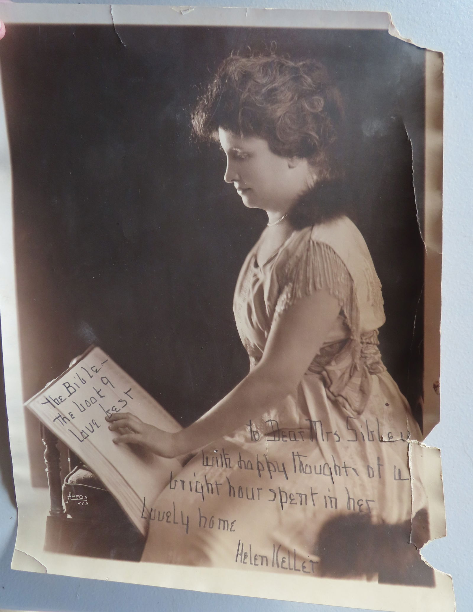 An autographed photo of Helen Keller printed in pencil "To Dear Mrs Sibley / with happy thoughts of: An autographed photo of Helen Keller printed in pencil "To Dear Mrs Sibley / with happy thoughts of a bright hour spent in her lovely home / Helen Keller". With her hand resting on a book, likely the