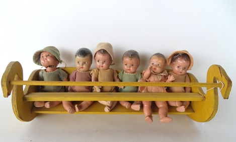 Dionne Quintuplet dolls in original cradle, plus another near matching dolls, all composition with