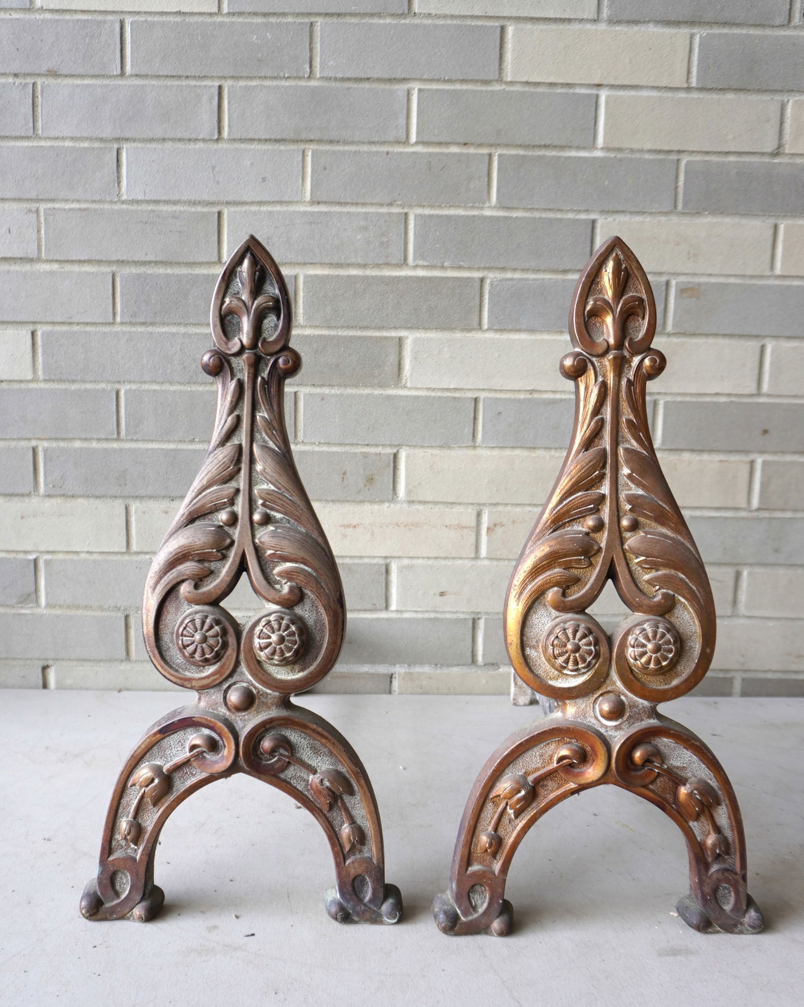 A pair of cast iron Arts & Crafts andirons with original bronze finish, decorated with acanthus: A pair of cast iron Arts & Crafts andirons with original bronze finish, decorated with acanthus leaves, rosettes and bell flowers on the legs and having a fleur de lis finials. Good condition. Measure