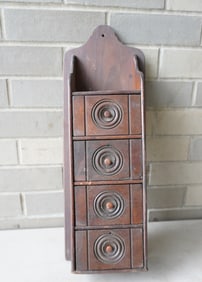 A 4 drawer wooden wall hanging spice box with carved drawer fronts having concentric circles
