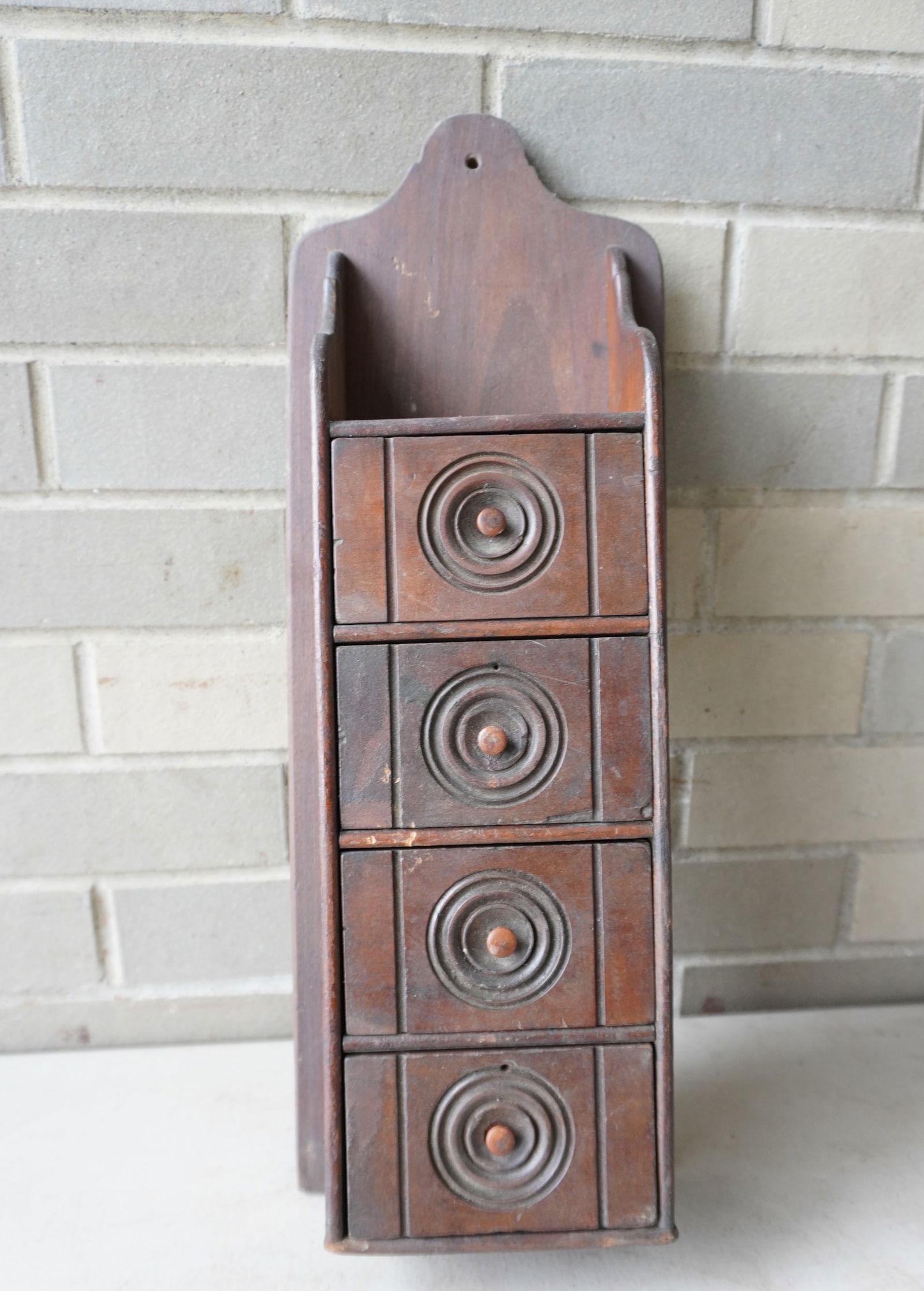 A 4 drawer wooden wall hanging spice box with carved drawer fronts having concentric circles (1 of 4)