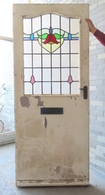 An Art Deco door having a stained and leaded glass upper panel with floral motif surrounded by