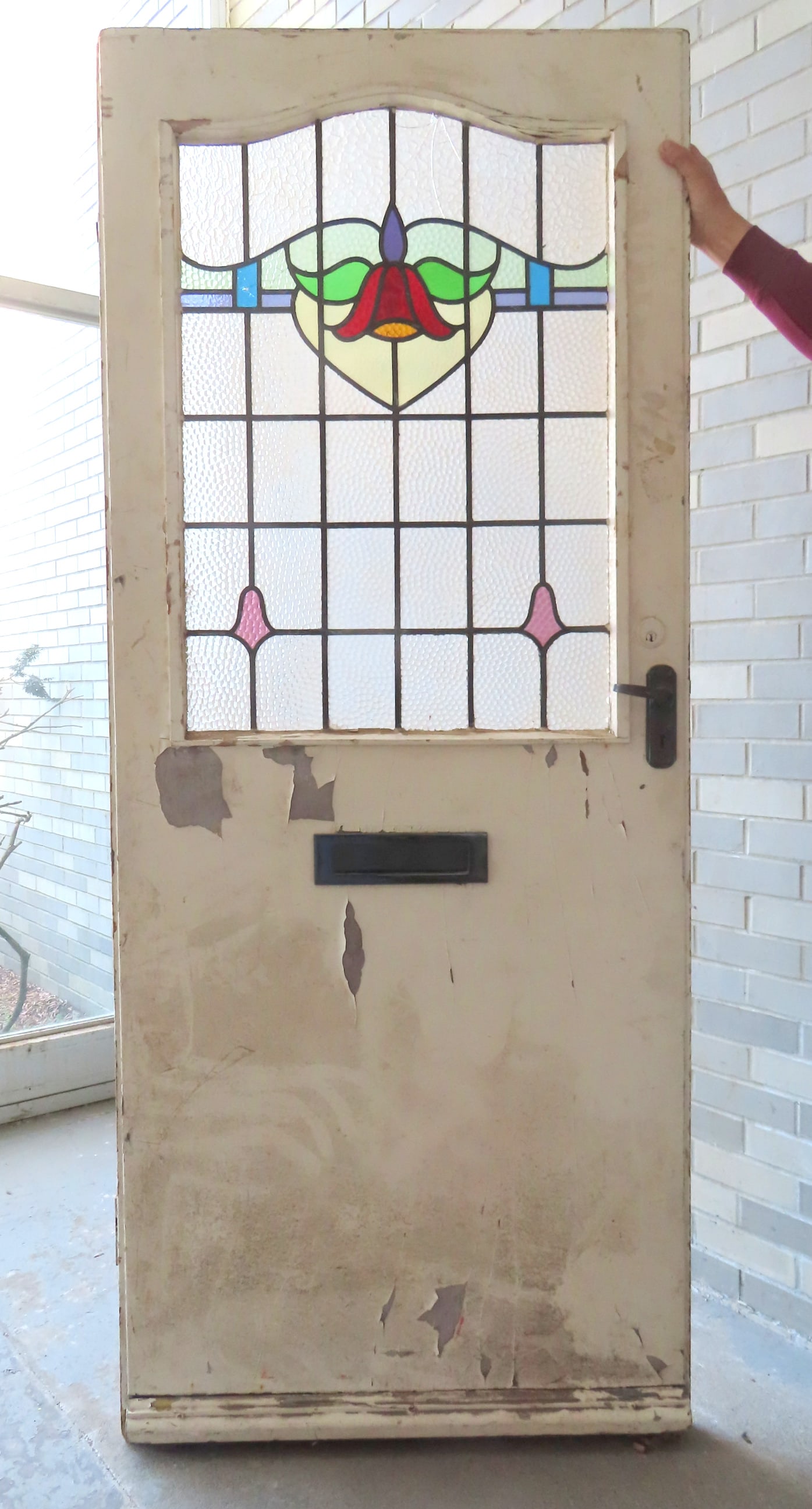 An Art Deco door having a stained and leaded glass upper panel with floral motif surrounded by: An Art Deco door having a stained and leaded glass upper panel with floral motif surrounded by opaque bubble-glass panels - 3 glass panels with hairlines and one with glass losses (see photos). The lo