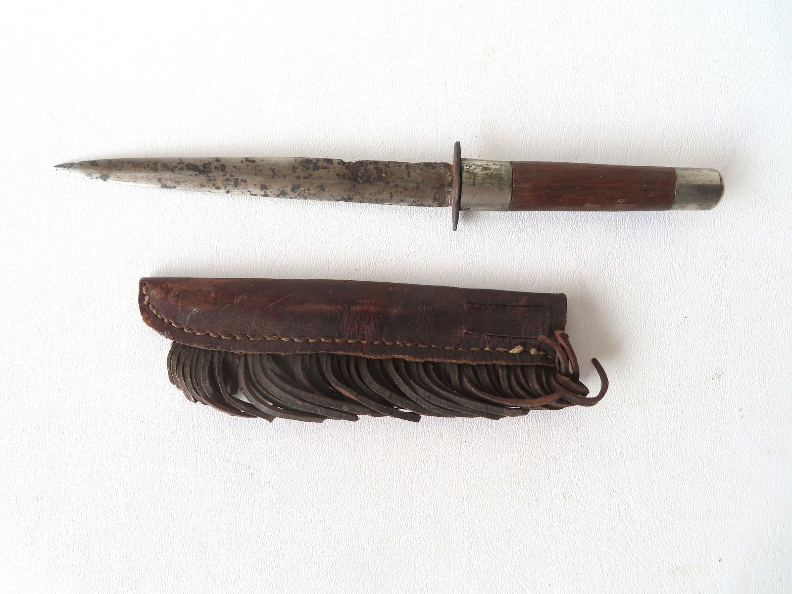 A frontier double edge Bowie knife with a hand made leather sheath with fringe, 19th century. Some (1 of 6)