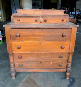 A late Sheraton chest of drawers having 2 short drawers on top, over 4 drawers, shaped backsplash