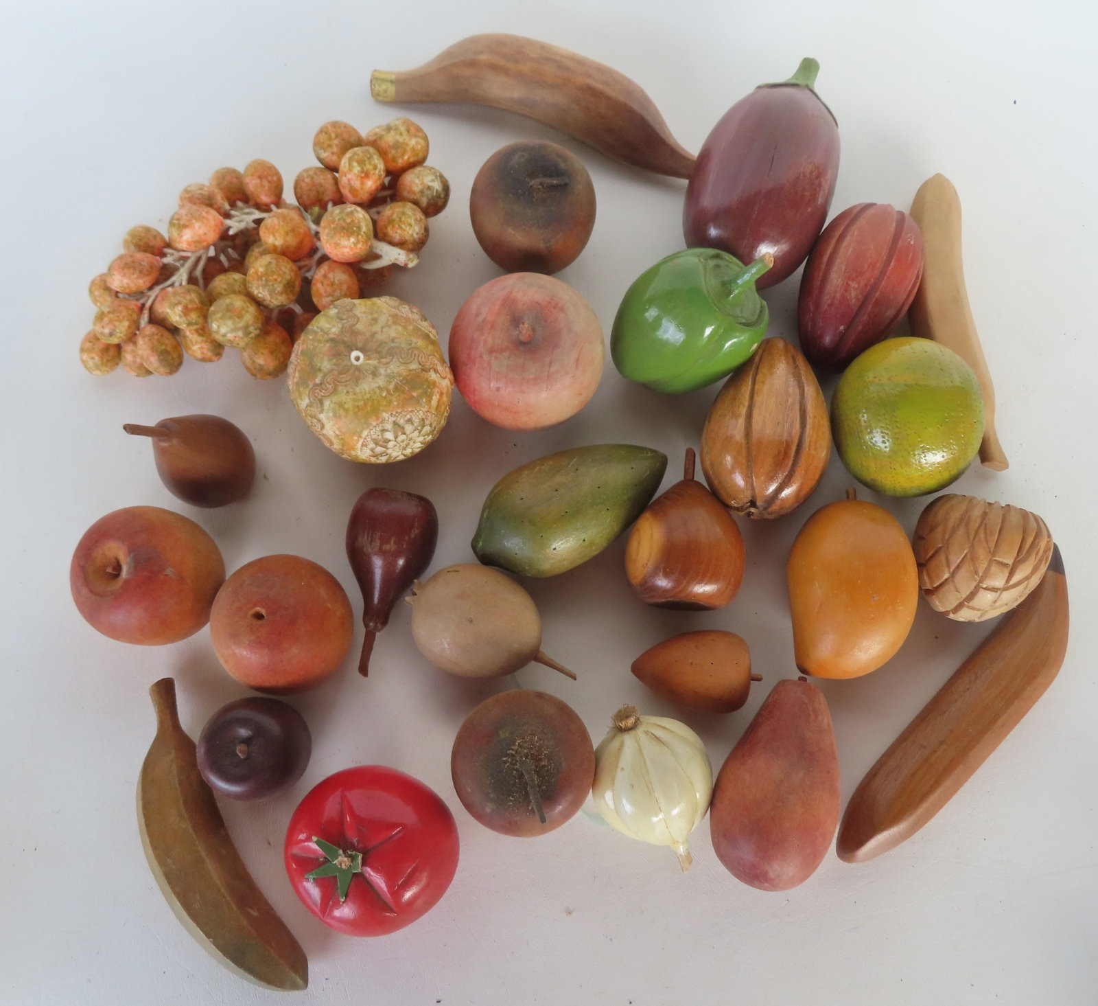 A grouping of mostly wooden fruit, some hand painted, 20th century. The largest, the composition gra: A grouping of mostly wooden fruit, some hand painted, 20th century. The largest, the composition grapes, measures 8"L. Most in good condition.