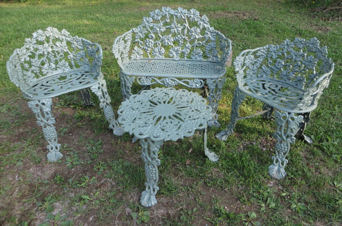 Four pieces of cast iron garden furniture in the grape : Four pieces of cast iron garden furniture in the grape pattern including settee with ornate grated seat, 2 matching chairs and matching end table - early to mid 20th century - newer green paint.