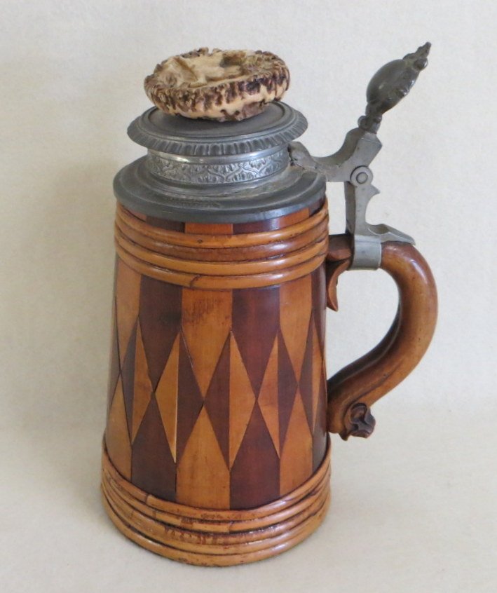Treenware tankard with pieced diamond pattern wooden bo: Treenware tankard with pieced diamond pattern wooden body, pewter lid (repaired) carved horn button of running stag on top of lid, signed and dated 1902 on base. 9.25"H.