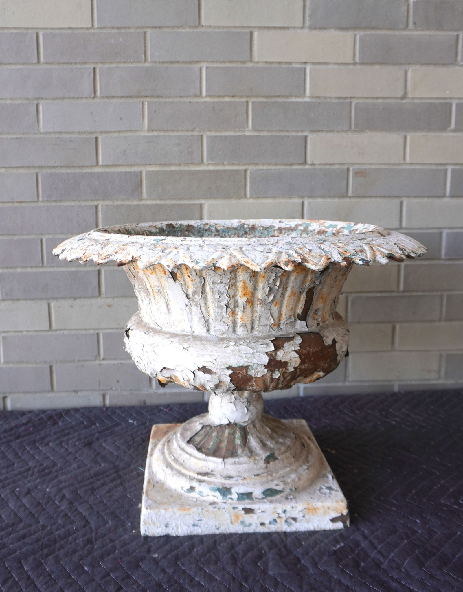 Cast iron garden urn with a leaf shaped flared edge, 1 piece construction, 19th century - layers of: Cast iron garden urn with a leaf shaped flared edge, 1 piece construction, 19th century - layers of old paint, note the drain spigot near bottom of urn - some surface rust, but overall good condition.