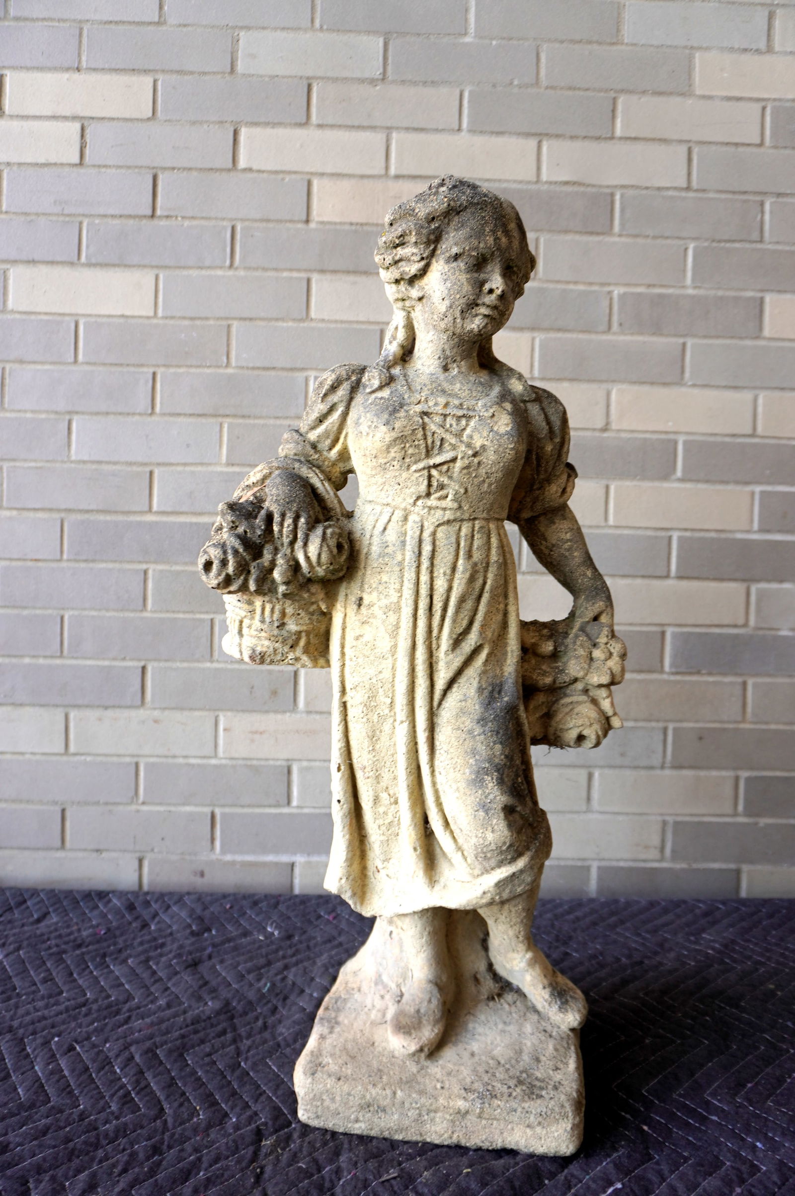 A concrete garden sculpture of a young lady holding flowers in both hands, probably mid 20th: A concrete garden sculpture of a young lady holding flowers in both hands, probably mid 20th century. Measures 14"W x 8 1/2 square at base x 29 1/2"H. Good condition.