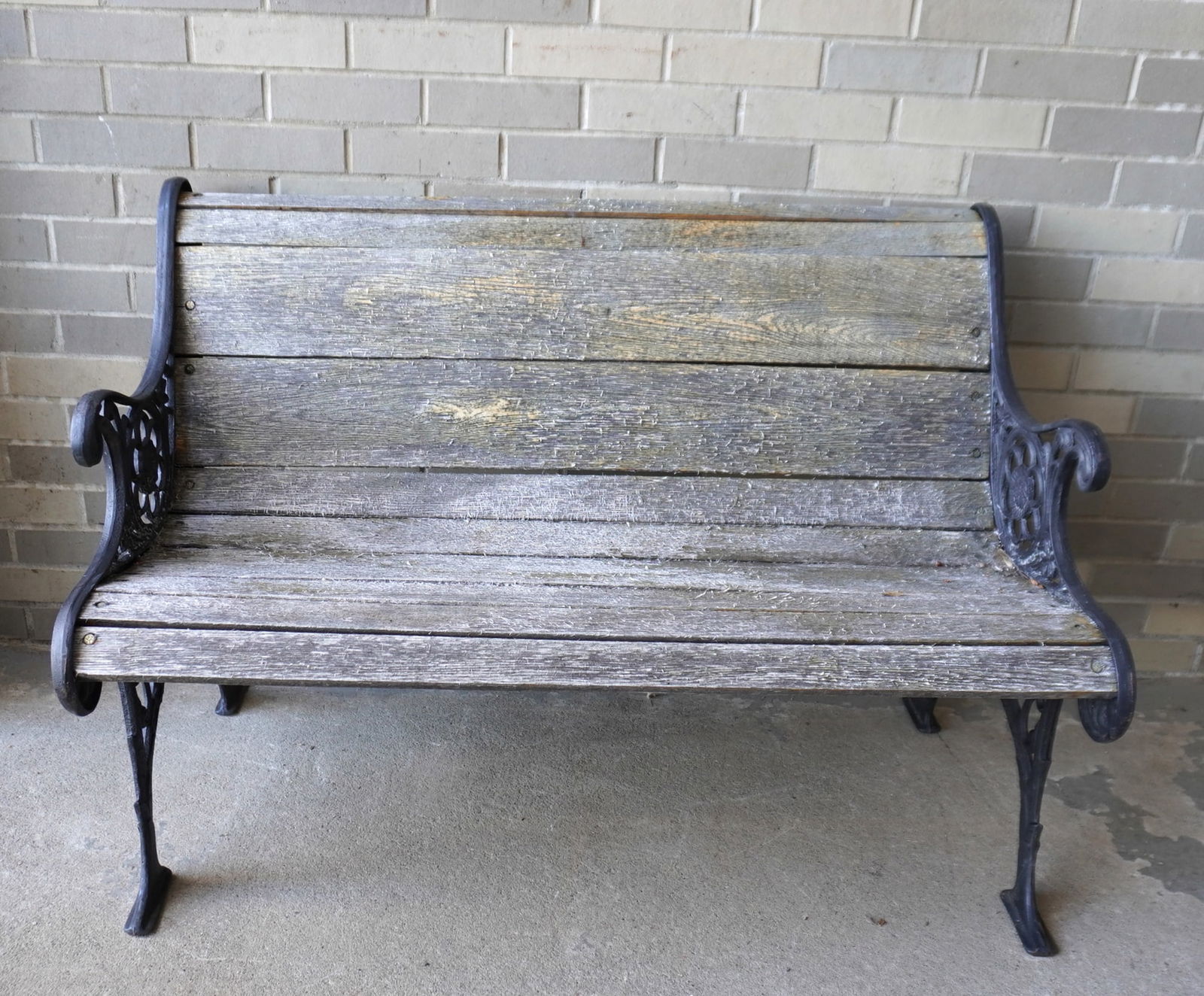 A park bench with ornate cast iron sides and horizontal oak slats in seat and back, probably late (1 of 4)