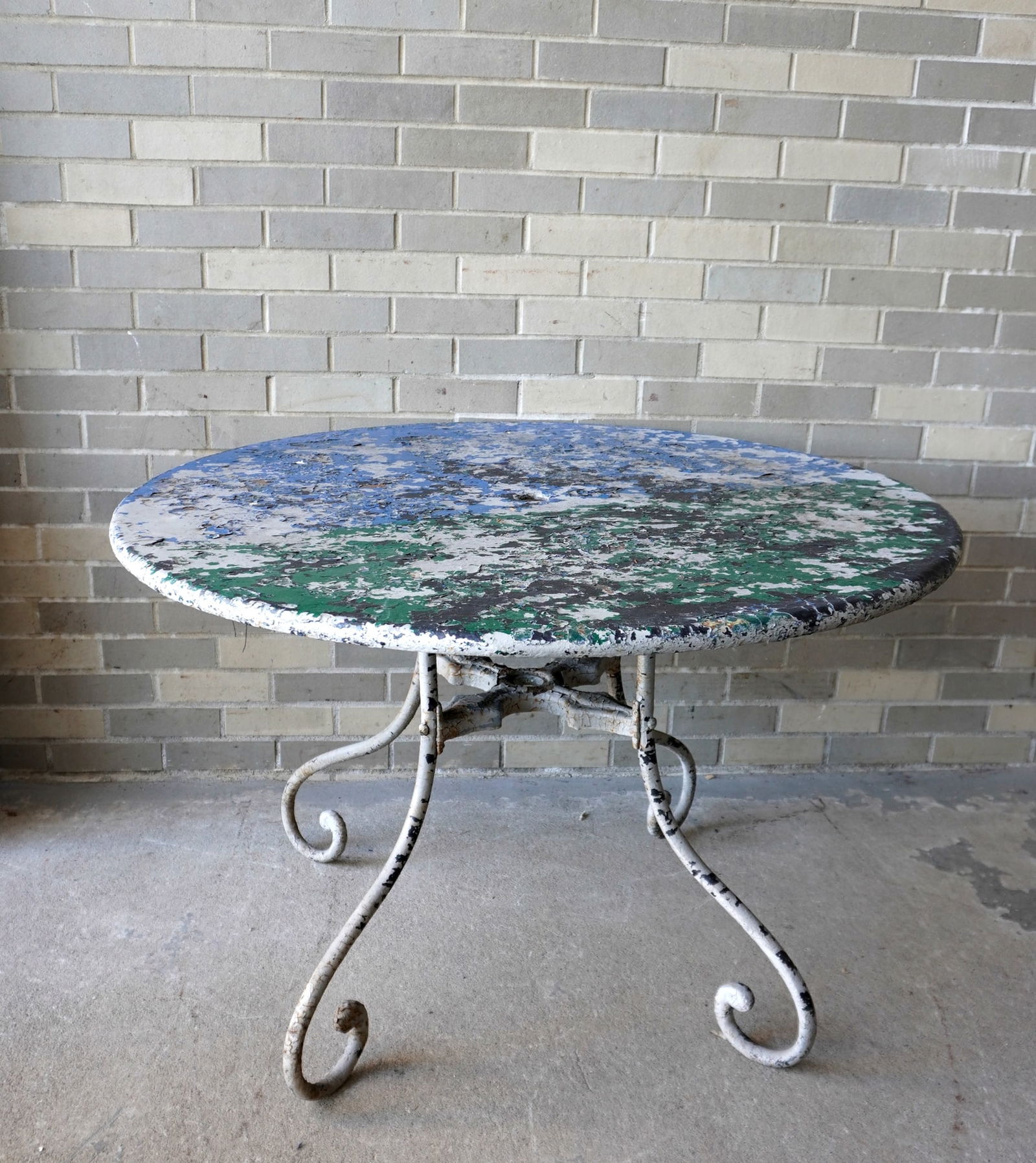 A round patio table with a painted sheet iron top mounted on an iron base with 4 scrolled legs with (1 of 5)