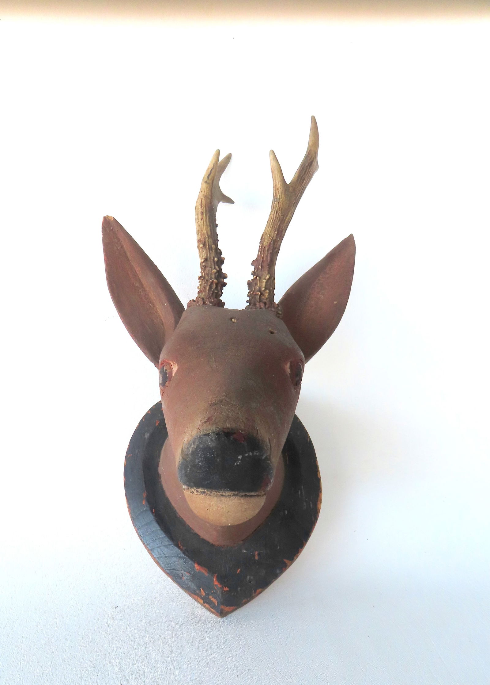 A folk art carved wooden deer head in original painted mounted on a heart shaped plaque, 19th: A folk art carved wooden deer head in original painted mounted on a heart shaped plaque, 19th century. Measures 8 1/2"W x 9"D x 14"H.