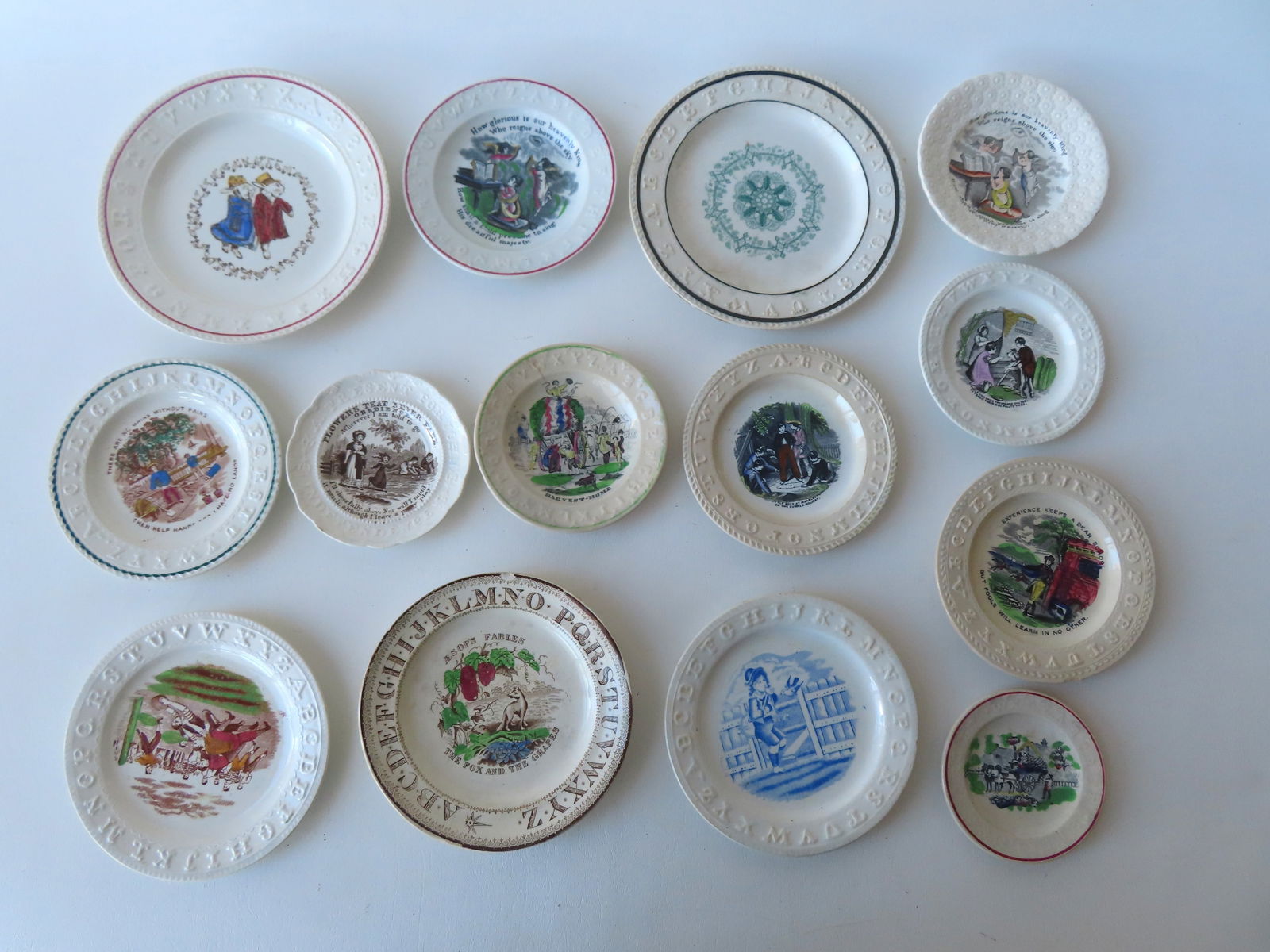 Grouping of 14 early alphabet plates, most Staffordshire transferware and some with mottos, 19th: Grouping of 14 early alphabet plates, most Staffordshire transferware and some with mottos, 19th century. Eight are in very good condition, with no damage, and 6 with hairlines or minor chips - see ph